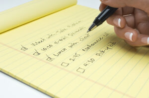 Closeup,Of,Female,Hand,Checking,Notepad,With,Reminders,Written,Over