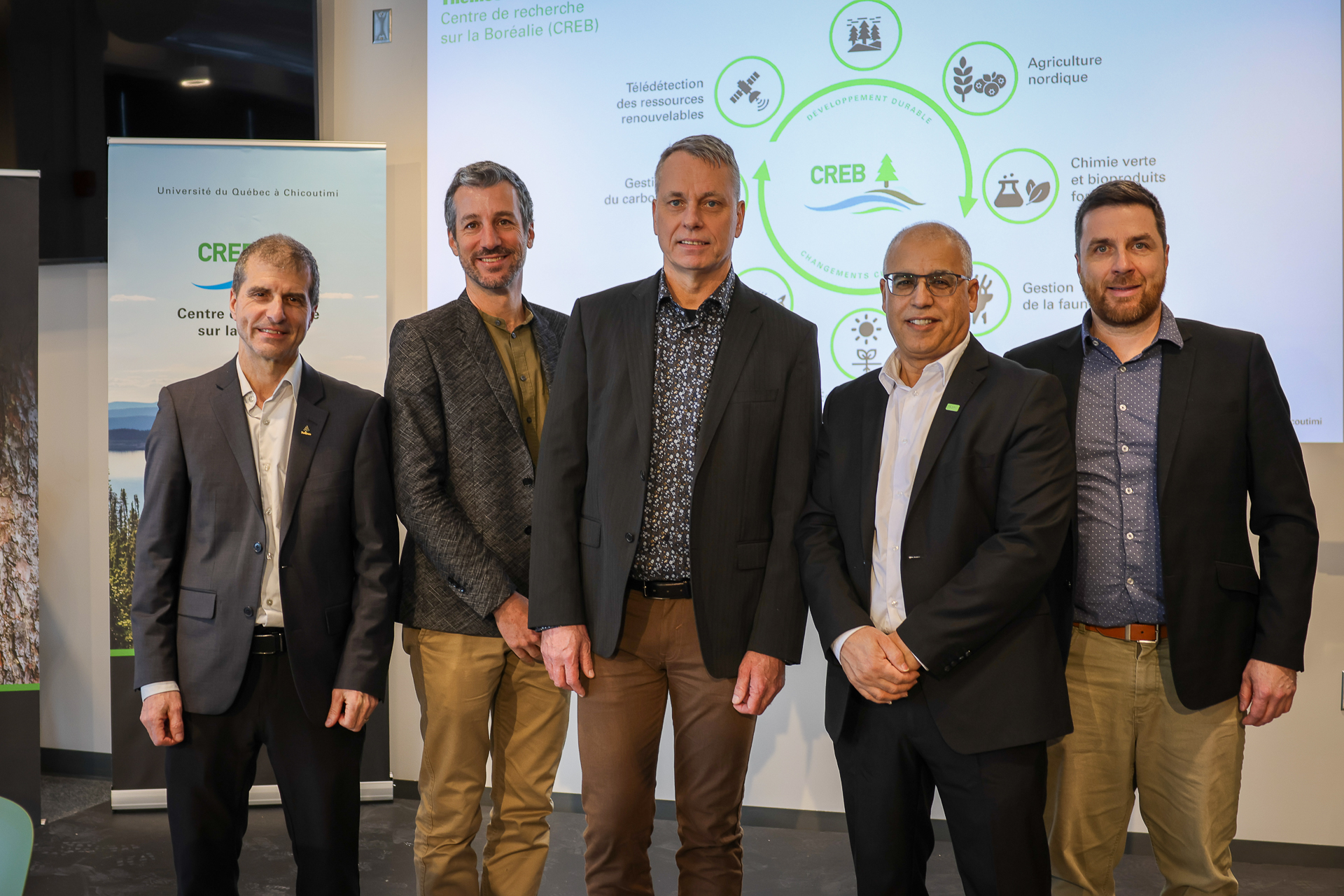 Group of five men pictured in front of a screen and banner. Domtar is part of a research partnership with Boisaco and UQAC's CREB to advance sustainable forest management research in Quebec.