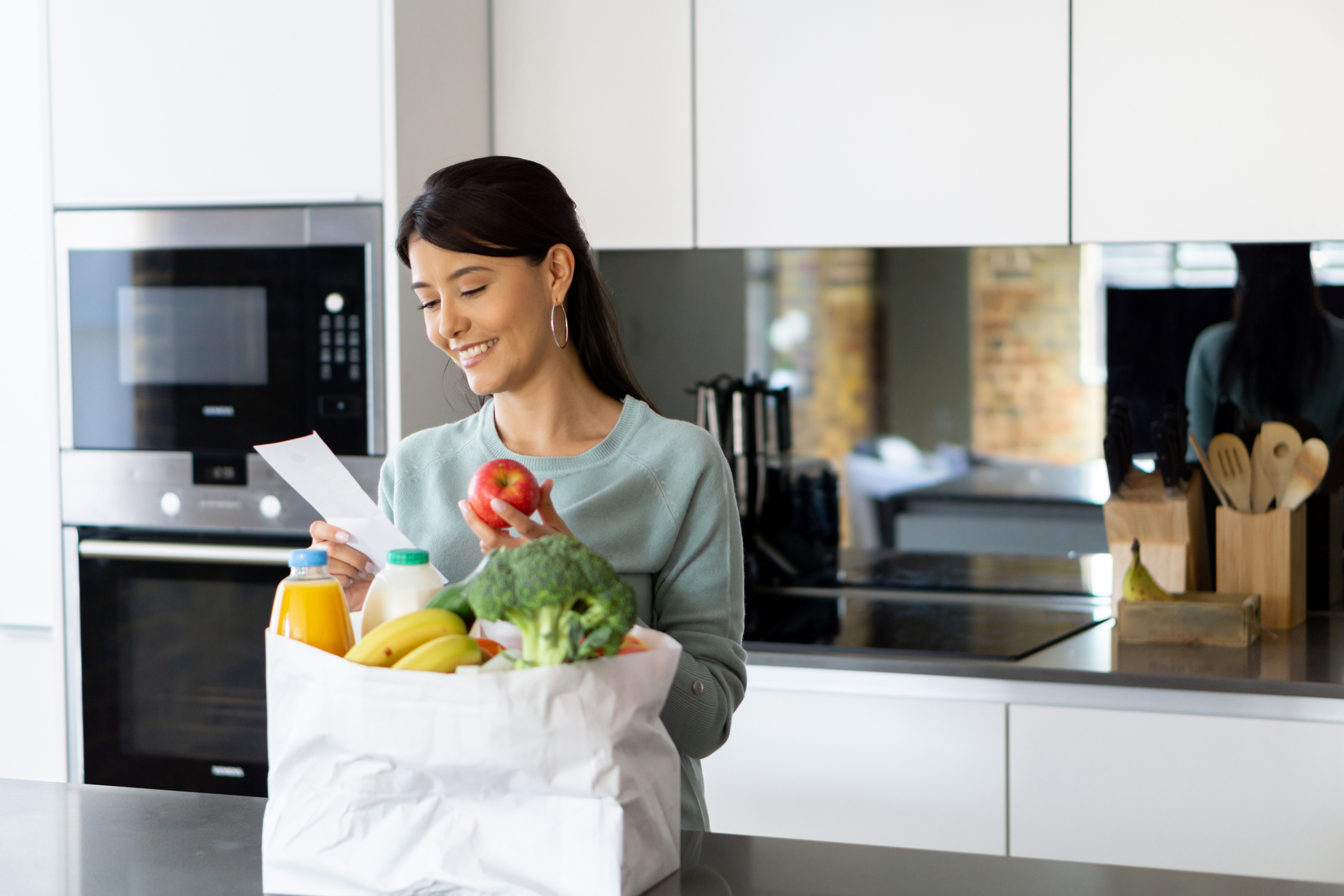 Portrait of a happy woman checking her shopping list at home after grocery shopping