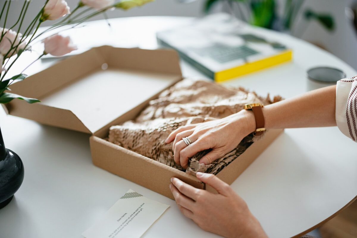 Close up shot of anonymous woman's hands removing the wrapping paper to reveal the content of a gift box she received.
