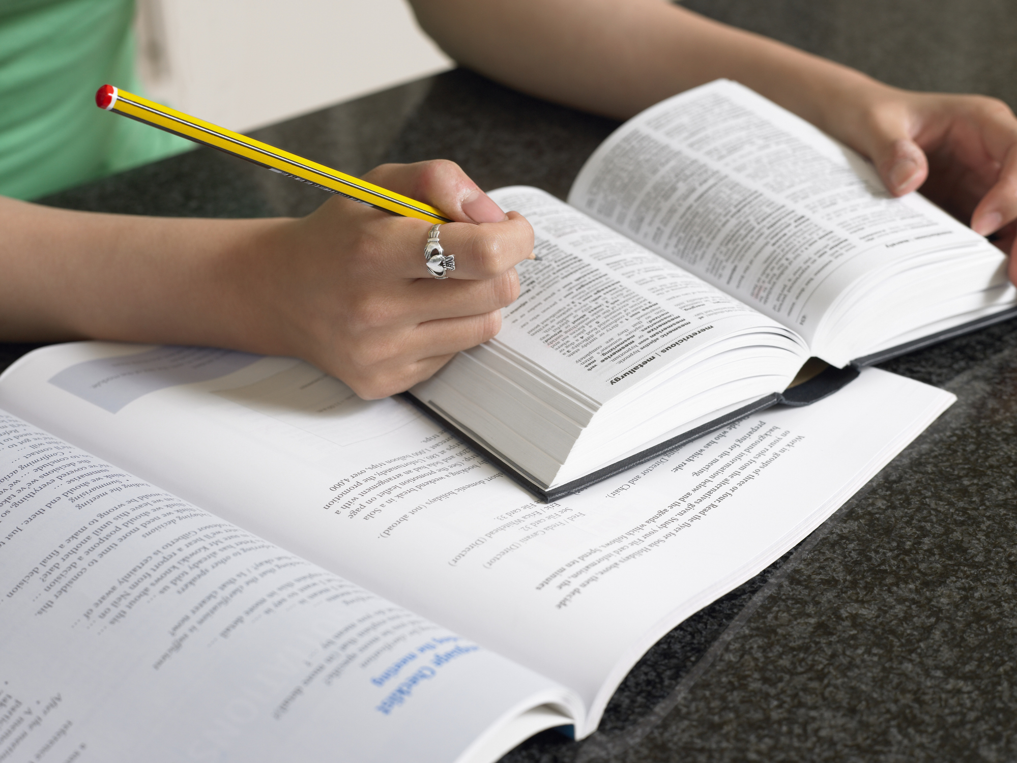 Student taking notes with dictionary and textbook