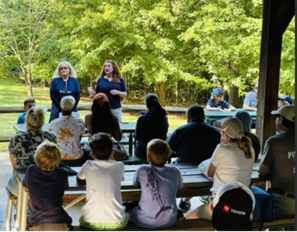 Paige Goff presents to a group in an outdoor park-like setting.
