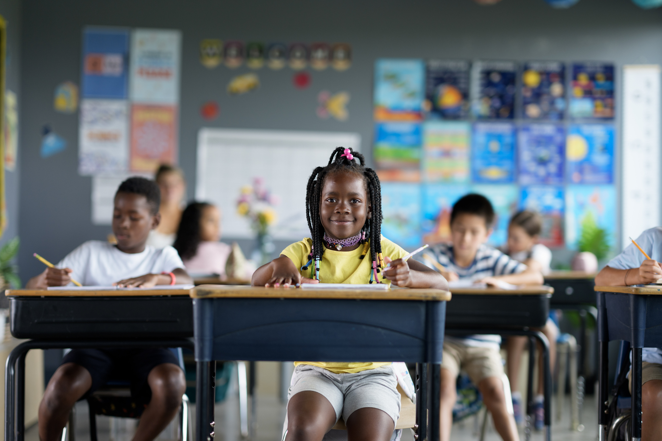 Diverse group of primary school students studying in a colorful and interactive classroom setting, fostering creativity and collaboration. Focused on teamwork and academic development in an inclusive learning space.